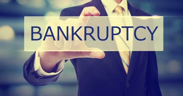 Business man holding Bankruptcy on blurred abstract background