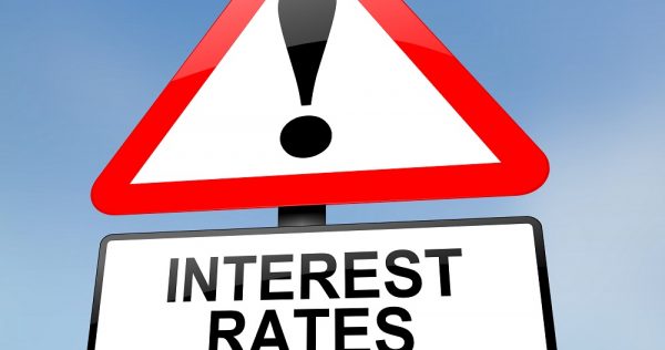 Illustration depicting a red and white triangular warning sign with an interest rates concept. Blurred sky background.